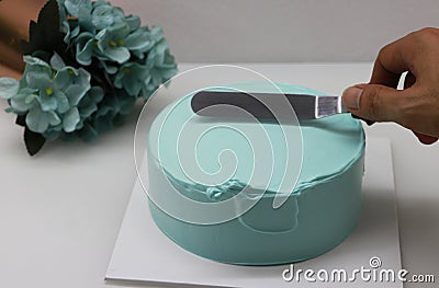 Hand is using equipment Scrape the green buttercream. To decorate the green pound cake Stock Photo