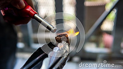 Hand using a gas lighter starter to ignite camping charcoal cock fire starter Stock Photo