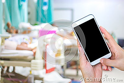 Hand using phone black screen on blurred hospital. Stock Photo