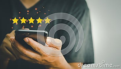 Hand using phone holding 5 stars on hands.Customer satisfaction and marketing survey rating concept Stock Photo