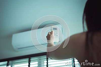 Hand using a remote control to activating air conditioning,Female operating remote controller at home Stock Photo