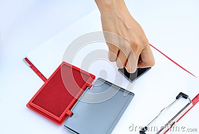 Hand using rubber stamper with red Ink padbox on white paper Stock Photo