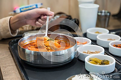 Hand using spoon scooping spicy kimchi soup and vegetable pickle on cup Stock Photo