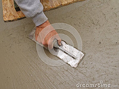 Hand using trowel to finish concrete slab Stock Photo