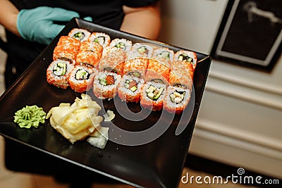 Hand Waiter holding Set Delicious fresh Sushi slate plate, Japanese raw fish in traditional restaurant. Philadelphia Stock Photo