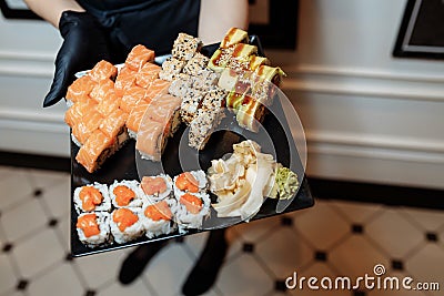 Hand Waiter holding Set Delicious fresh Sushi slate plate, Japanese raw fish in traditional restaurant. Philadelphia Stock Photo