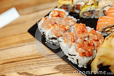 Hand Waiter holding Set Delicious fresh Sushi slate plate, Japanese raw fish in traditional restaurant. Philadelphia Stock Photo