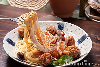 The hand was holding a fork, cutting spaghetti, ketchup, meatballs Stock Photo