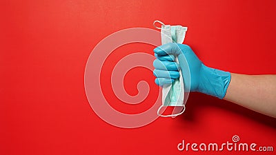 Hand wear glove and holding face Mask on red background Stock Photo