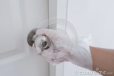 Hand wearing plastic glove open the door, protecting from bacteria and germs Stock Photo