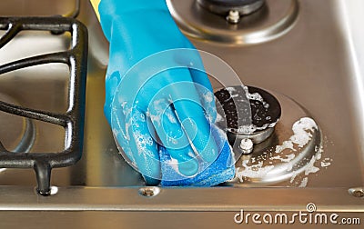 Hand wearing rubber glove while cleaning stove top range with s Stock Photo