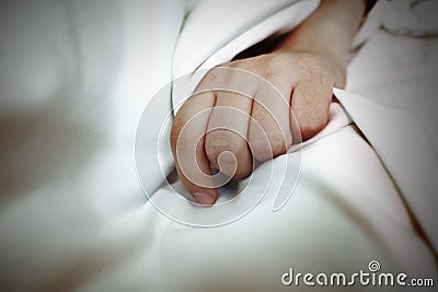 Hand on the white sheet as a concept, a metaphor of disease, ind Stock Photo