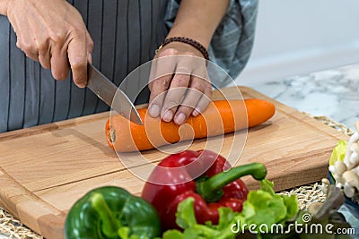 hand woman carrot with kitchen knife on cutting board. Chef cuts the vegetables into a meal Stock Photo