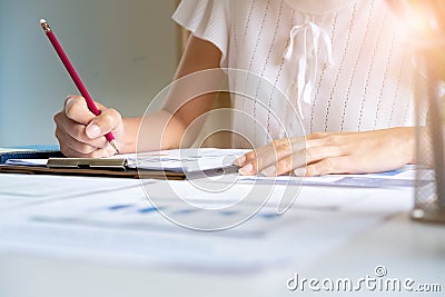 Hand of woman catch yellow pencil, Woman working on desk, orange light flare Stock Photo