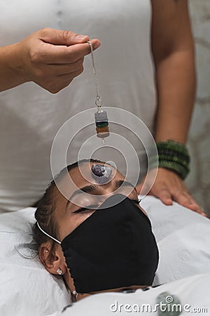 Hand of a woman healer applying reiki and energy therapies through the use of a pendulum Stock Photo