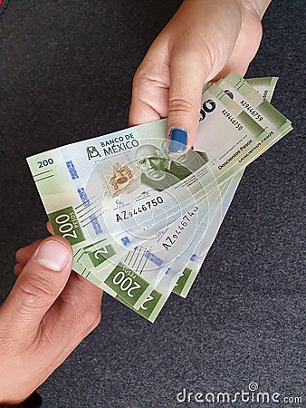 hand of a woman paying with Mexican money and hand of a man receiving Stock Photo