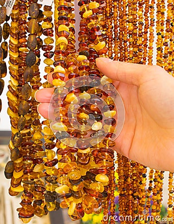 Hand of woman with shiny womanly amber necklaces on stall at the bazaar Stock Photo