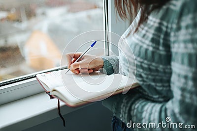 Hand of woman unrecognizable writes down necessary words with notepad for notes, pen on paper. Stock Photo