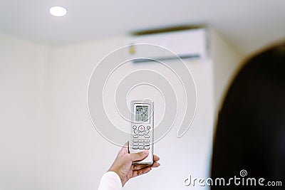 Hands woman using remote control to activating 25 degree celsius,Concept save energy and save world Stock Photo