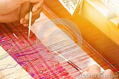 Hand of a women works on silk weaving with traditional hand weaving loom. Stock Photo