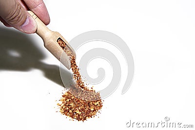 hand with wooden spoon pouring dried chili spices or chili peppers into a mound Stock Photo