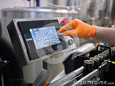 Hand of a worker touching the screen of an electronic machine of a brewery Stock Photo