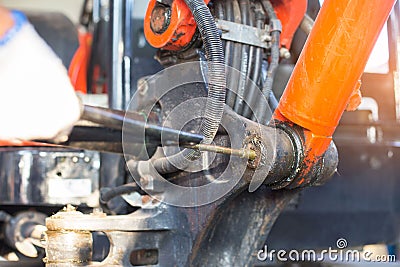 Hand of a workman greasing the grease nipple of a hydraulic cylinder the backhoe Stock Photo