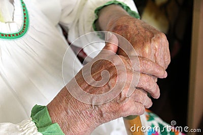 Female old wrinkled hands hold wooden cane Stock Photo