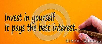 Hand writing `invest in yourself it pays the best interest`, isolated on orange background. Business concept, copy space Stock Photo