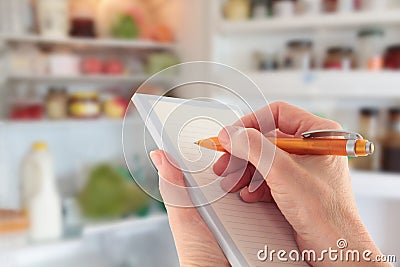 Hand Writing a List in front of an open Fridge Stock Photo