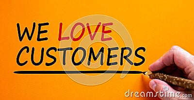 Hand writing `we love customers`, isolated on beautiful orange background. Business concept, copy space Stock Photo