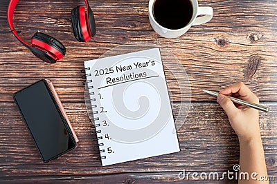 Hand writing 2025 New Year's Resolutions text on Notepad Stock Photo