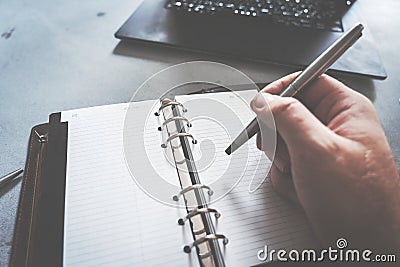 Hand writing in notebook with laptop as background Stock Photo