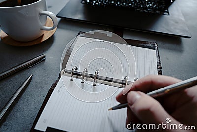 Hand writing in notebook with laptop as background Stock Photo