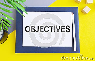 Hand writing Objectives to do list on white paper above Notebook, yellow background Stock Photo