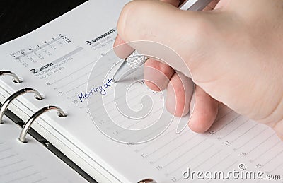 Hand writing with silver pen on open agenda Stock Photo
