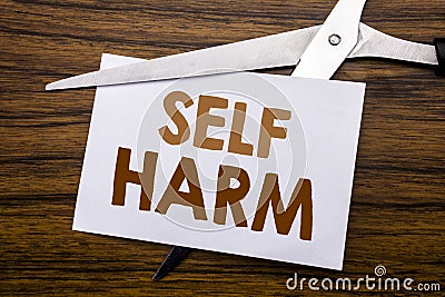 Hand writing text caption inspiration showing Self Harm. Business concept for Selfharm Mental Aggression Written on note, wooden b Stock Photo