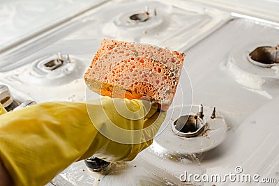 A hand in a yellow glove holds a dirty sponge Stock Photo