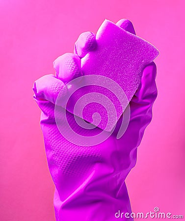 A hand in yellow rubber gloves holds a dishwashing sponge on Stock Photo