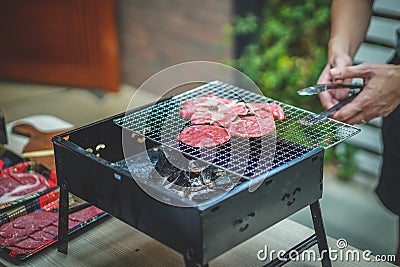 Young Man Grills Sliced beef on Charcoal Grill. Stock Photo
