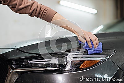 Hand of young man worker of auto service, wiping and polishing the headlights and hood Stock Photo