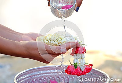 Hand of young woman pour water and flowers on the hands. older women and happy for the songkran festival. concept gives blessing Stock Photo
