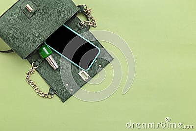 Handbag, phone, nail polish on green background. Monochrome. Minimal. Copy space Stock Photo