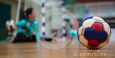 Handball ball on court floor. Blurred female goalkeeper background. Space for text, close up view. Stock Photo