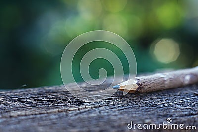 Handcraft pencil made of wood on wooden table with smooth green garden background, copy space Stock Photo