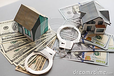 handcuffs, dollars, house figure on wooden background. violation of law. real estate fraud. Stock Photo