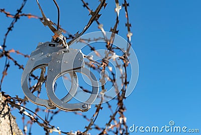 Handcuffs hang on barbed wire. Prison. Law and order. A crime Stock Photo