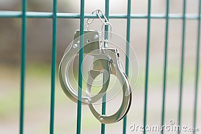 handcuffs hang on a metal grille Stock Photo