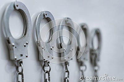 The handcuffs hang in a row on a chain on the wall Stock Photo