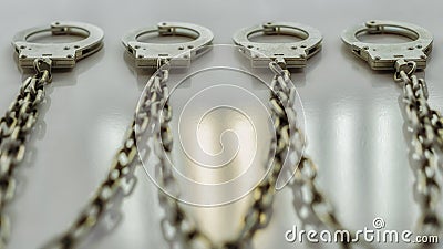 The handcuffs hang in a row on a chain on the wall Stock Photo